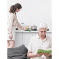 senior-woman-reading-book-in-front-of-woman-doing-housekeeping-work